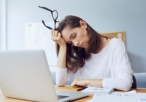 woman suffering from chronic pain seated at a computer desk